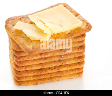 Crumbly aged cheddar on a stack of crackers, on a reflective white plate. Stock Photo