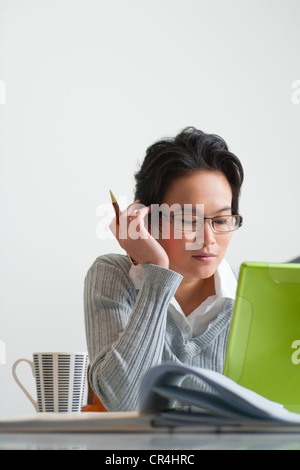 Portrait of young asian lady wearing long sleeve working and using social media on laptop with clean white background. Stock Photo