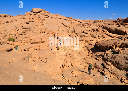 Group of tourists hiking through granite landscape, Hoggar, Ahaggar Mountains, Wilaya Tamanrasset, Algeria, Sahara, North Africa Stock Photo