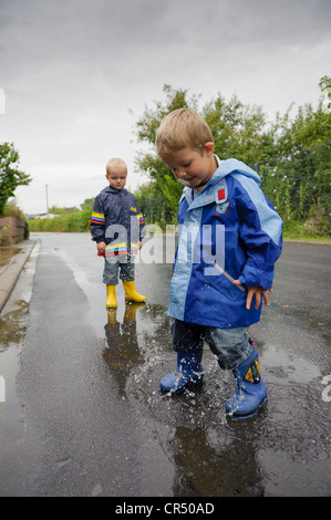 4-year-old boy jumping in a puddle on the road in the rain, Assamstadt, Baden-Wuerttemberg, Germany, Europe Stock Photo