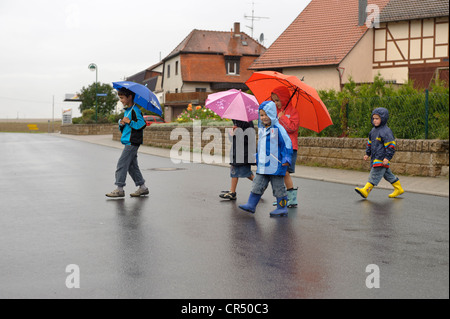 Five children, 3 to 8 years, crossing the street in the rain, Assamstadt, Baden-Wuerttemberg, Germany, Europe Stock Photo