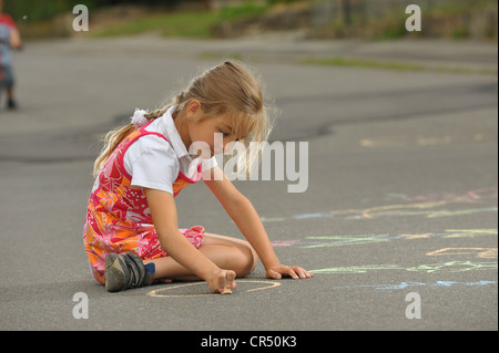 Girl, about 6 years, painting with chalk on asphalt Stock Photo