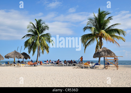 Bathers and palm trees on the beach of Playa Ancón, near Trinidad, Cuba, Caribbean Stock Photo