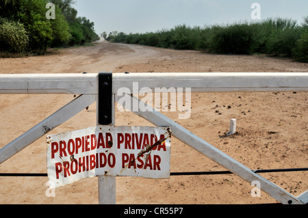 Sign on a gate 'Propiedad privada, Prohibido pasar', 'private property, access prohibited', marking the grounds of a major Stock Photo