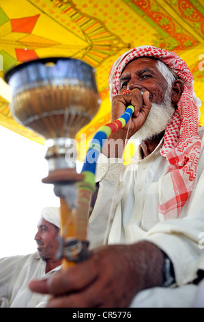 Elderly man with a white beard, smoking tobacco in a traditional pipe, waterpipe, Muzaffaragarh, Punjab, Pakistan, Asia Stock Photo