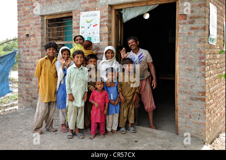 Family standing in front of their new house made of bricks that they received from a relief organisation, their old house was Stock Photo