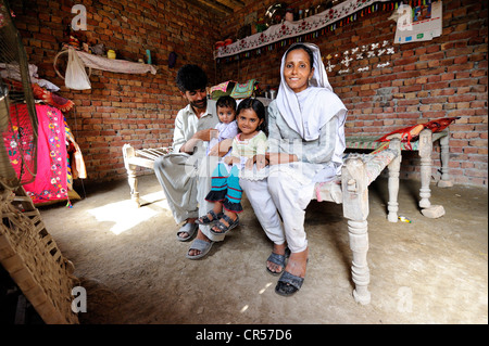 Family sitting in a new house made of bricks that they received from a relief organisation, their old house was destroyed during Stock Photo