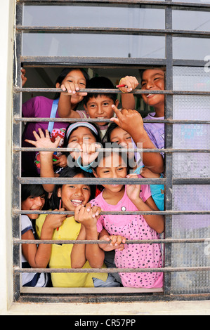 Laughing children behind the barred window of a school, poor district of Villa El Salvador, Lima, Peru, South America Stock Photo