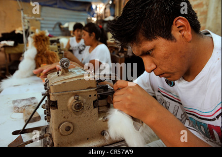 Young man working at a sewing machine, production of soft toys and carpets from alpaca fur in a small family business, Pachamac Stock Photo