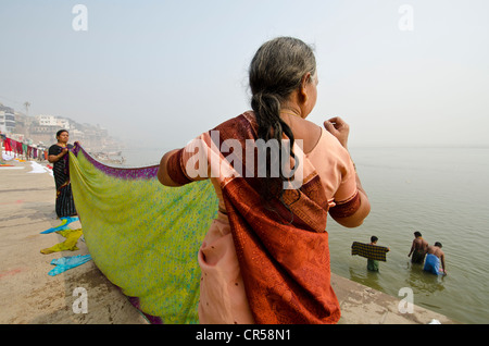 Woman washing clothes as part of the ritual bath in the holy river Ganges, Varanasi, Uttar Pradesh, India, Asia Stock Photo