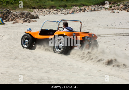 VW beach buggy driving on a sandy beach under a blue sky Stock Photo