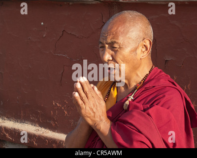 Buddhist monk praying in front of Boudnath stupa, Boudnath, Kathmandu, Nepal, South Asia Stock Photo