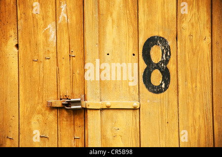 Old wooden garage door with number eight written on it. Stock Photo