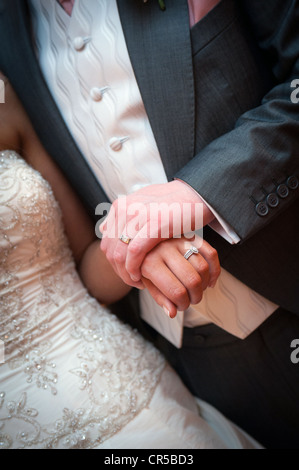 A bride and groom hold hands displaying their wedding rings Stock Photo