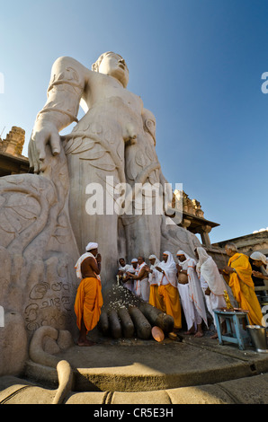 A group of Jain pilgrims doing a special pooja in front of the gigantic statue to receive the blessings of Bahubali by the local Stock Photo