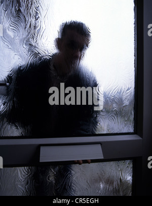 Silhouette of a man behind a frosted glass door, outside looking in. Posed by models Stock Photo