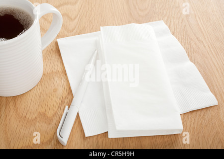 White paper napkin on wooden table with pen for making notes, and mug of coffee, Stock Photo