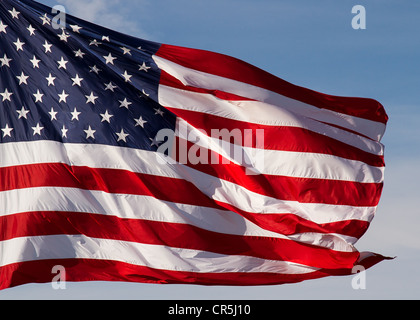 A crisp, brilliant American flag flies in a steady breeze with blue sky behind. Stock Photo