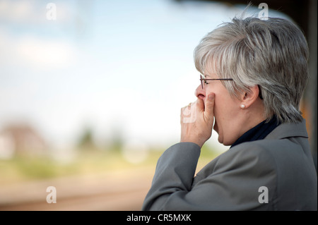 Woman, 50 +, yawning and holding her hand over her mouth Stock Photo