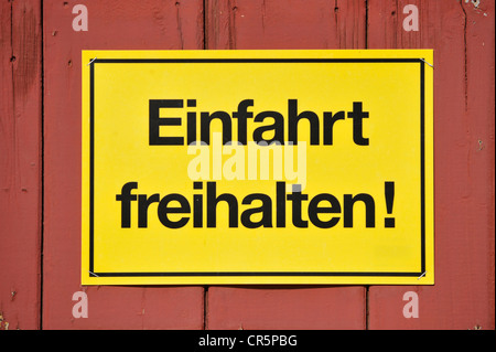 Sign, Einfahrt freihalten! German for Keep entrance clear, yellow on a red wooden gate, Germany, Europe Stock Photo