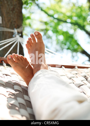 Feets in a hammock on a summer nature background.