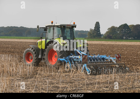 Tractor with a cultivator driving on a field, PublicGround Stock Photo