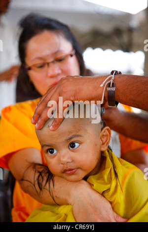 Child's hair being shaved with a razor, Hindu festival Thaipusam, Batu Caves limestone caves and temples, Kuala Lumpur, Malaysia Stock Photo