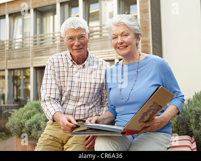 Germany, Cologne, Senior couple with photo album in front of nursing home, portrait Stock Photo