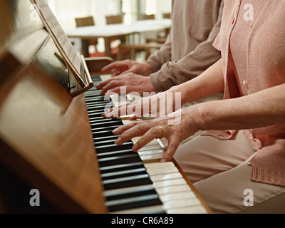 Germany, Cologne, Senior couple playing piano in nursing home Stock Photo