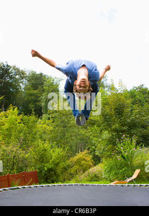 Austria, Young man jumping on trampoline Stock Photo