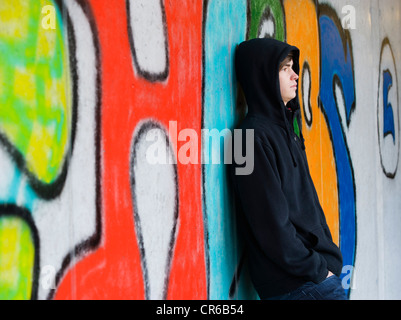 Austria, Mondsee, Young man standing at graffiti wall Stock Photo