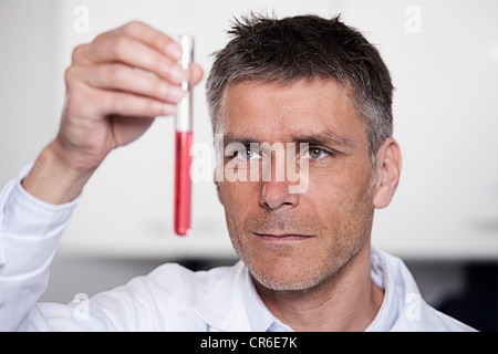 Germany, Bavaria, Munich, Scientist holding red liquid in test tube for medical research in laboratory Stock Photo
