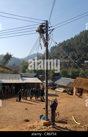 Laos , Hmong village Nam Kha , village electrification by lao-german company Sunlabob and NGO, worker in power pole doing the wiring of a off-grid electric network, the energy comes from small hydro turbine Stock Photo