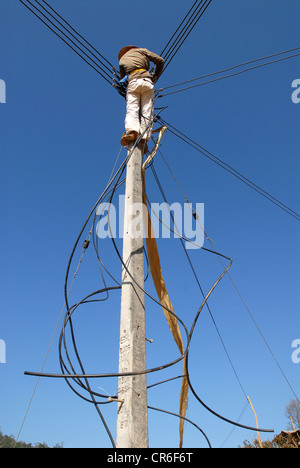 Laos , Hmong village Nam Kha , village electrification by lao-german company Sunlabob and NGO, worker doing wiring in power pole for a off-god net in the village, the power is produced from small hydro turbine Stock Photo