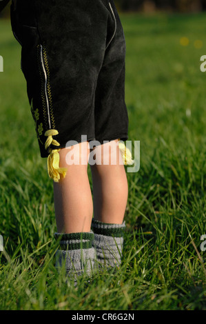 5-year old boy wearing traditional leather pants and dress socks standing in the grass Stock Photo