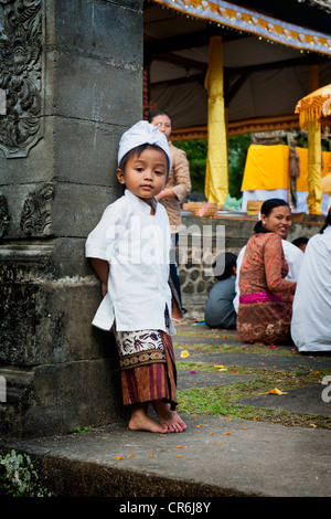 A young Balinese boy poses in traditional dress for a photo during a Hindu Temple anniversary called an Odalan. Stock Photo