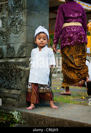 A young Balinese boy poses in traditional dress for a photo during a Hindu Temple anniversary called an Odalan. Stock Photo