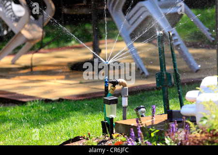 Sprinkler in backyard of suburban home Long Island NY Stock Photo