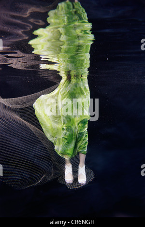 Mixed race woman in dress swimming under water