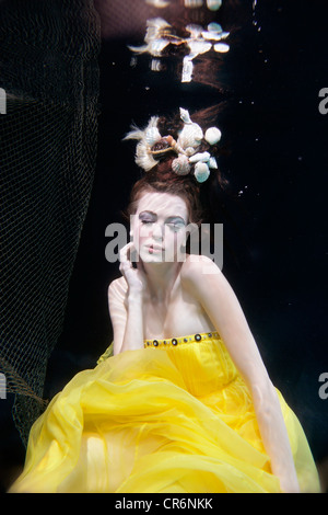Mixed race woman in dress swimming under water