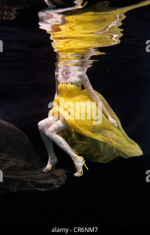 Mixed race woman in dress swimming under water