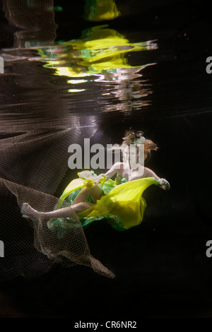 Caucasian woman in dress swimming under water