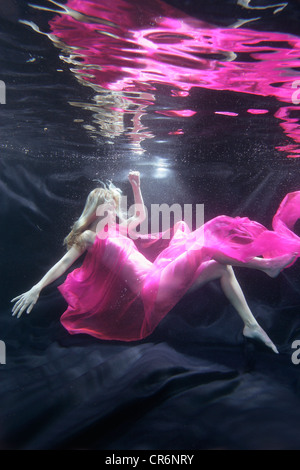 Caucasian woman in dress swimming under water