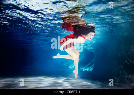 Caucasian woman in dress swimming under water Stock Photo