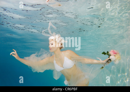Caucasian bride in bikini swimming under water Stock Photo