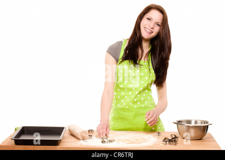 happy young woman pressing christmas molds in dough with white background Stock Photo