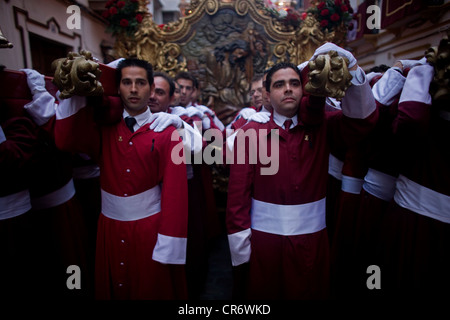 Men carry a throne on their shoulders during an Easter Holy Week procession in Puente Genil, Andalusia, Spain. Stock Photo