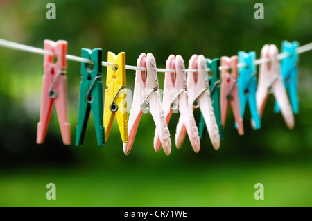 Various clothes-pegs on a washing line in a garden Stock Photo