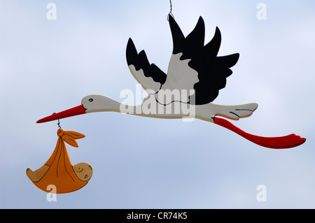 Stork figure carrying a baby in its beak, Hauptstrasse 88, Endingen, Baden-Wuerttemberg, Germany, Europe Stock Photo