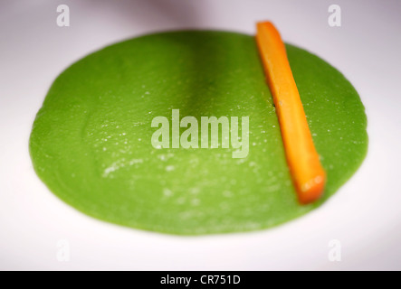 single chopped carrot sticks in lines on a bed of mushy peas on a white plate in a restaurant Stock Photo